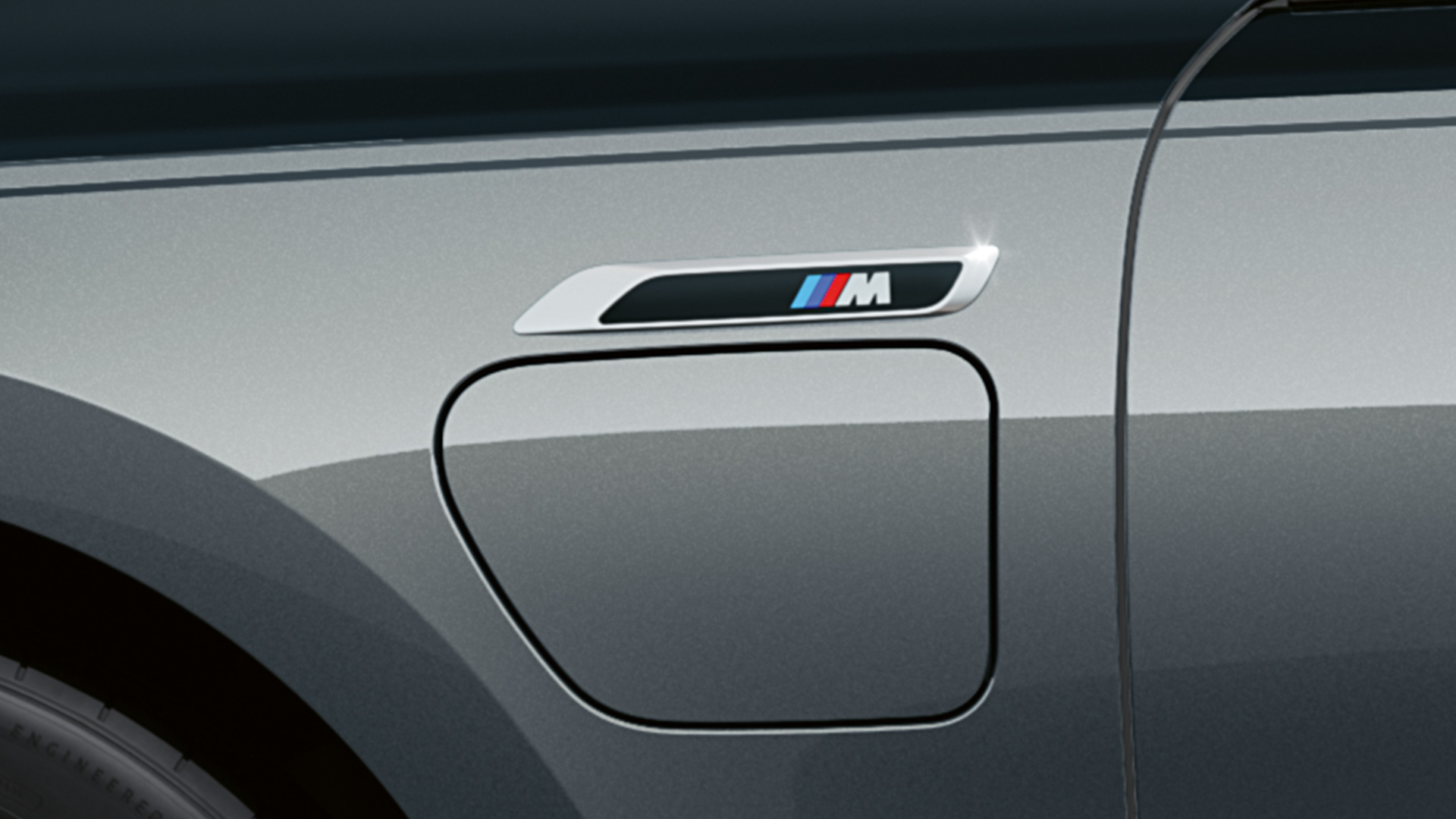 M badge BMW M760e xDrive G70 M badge BMW M760e xDrive G70 M Performance-pakket BMW Individual two-tone koetswerkkleur Saphirschwarz metallic BMW Individual Dravitgrau metallic close-up zijaanzicht