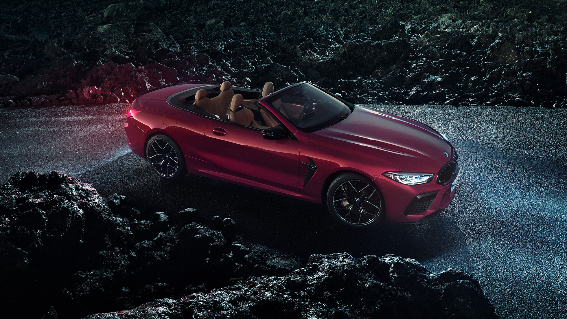 BMW M8 Competition Cabrio, vue de trois quarts de profil F91. BMW M8 Competition Cabrio en Motegi Rot metallic avec capote ouverte, vue de trois quarts de profil, à l’arrêt sur l’asphalte pendant la nuit F91.