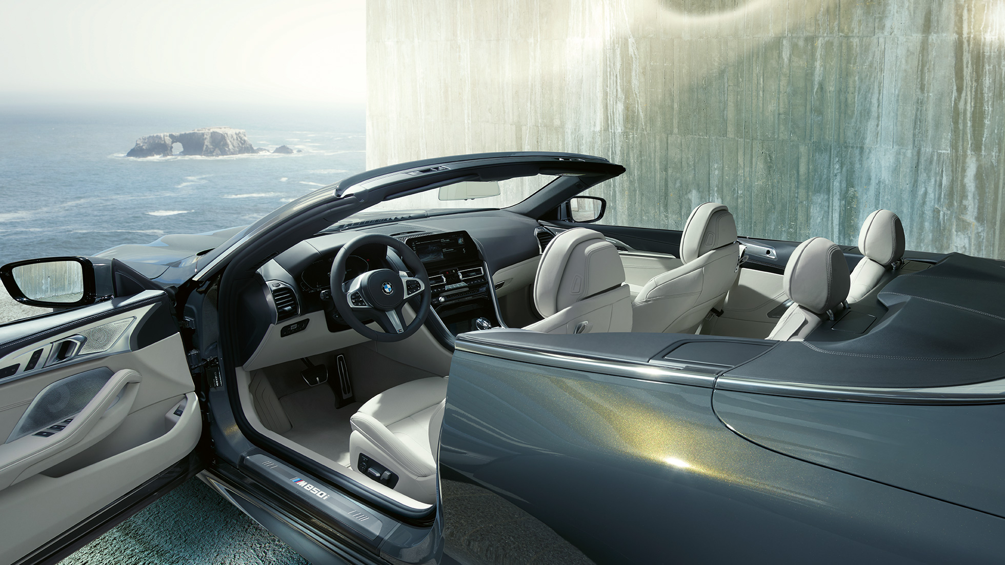 BMW M850i xDrive Cabrio, habitacle G14. BMW M850i xDrive Cabrio in Dravitgrau metallic avec capote ouverte, habitacle avec volant M en cuir et garnissage BMW Individual en cuir Merino Elfenbeinweiss G14.