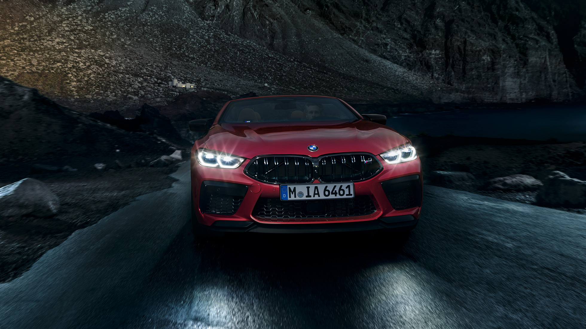 BMW M8 Competition Cabrio, vooraanzicht F91. BMW M8 Competition Cabrio in Motegi Rot metallic met brandende koplampen, vooraanzicht, ‘s nachts in beweging F91.