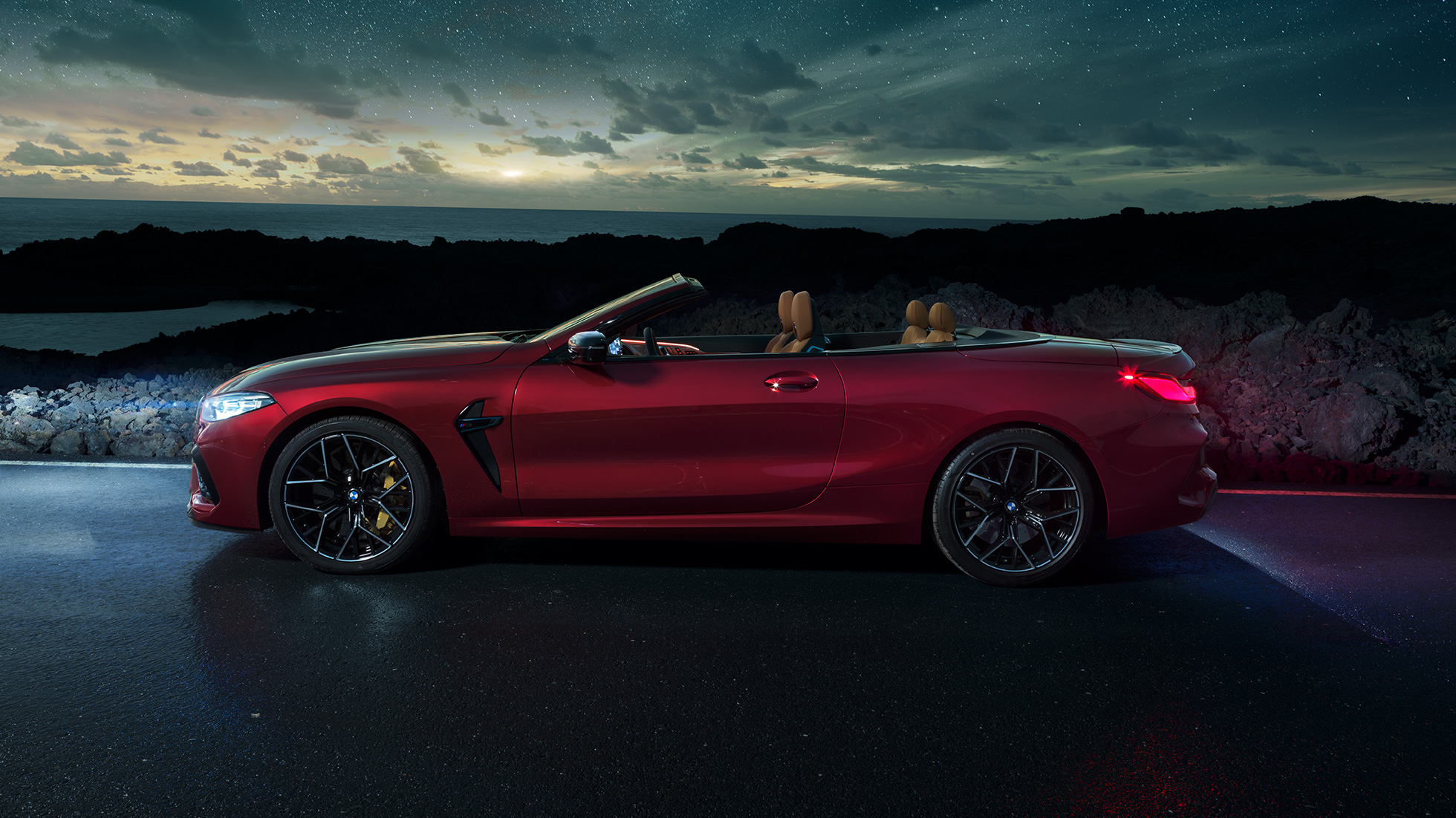 BMW M8 Competition Cabrio, vue de profil F91. BMW M8 Competition Cabrio en Motegi Rot metallic avec capote ouverte, vue de profil nocturne sous un ciel étoilé F91.