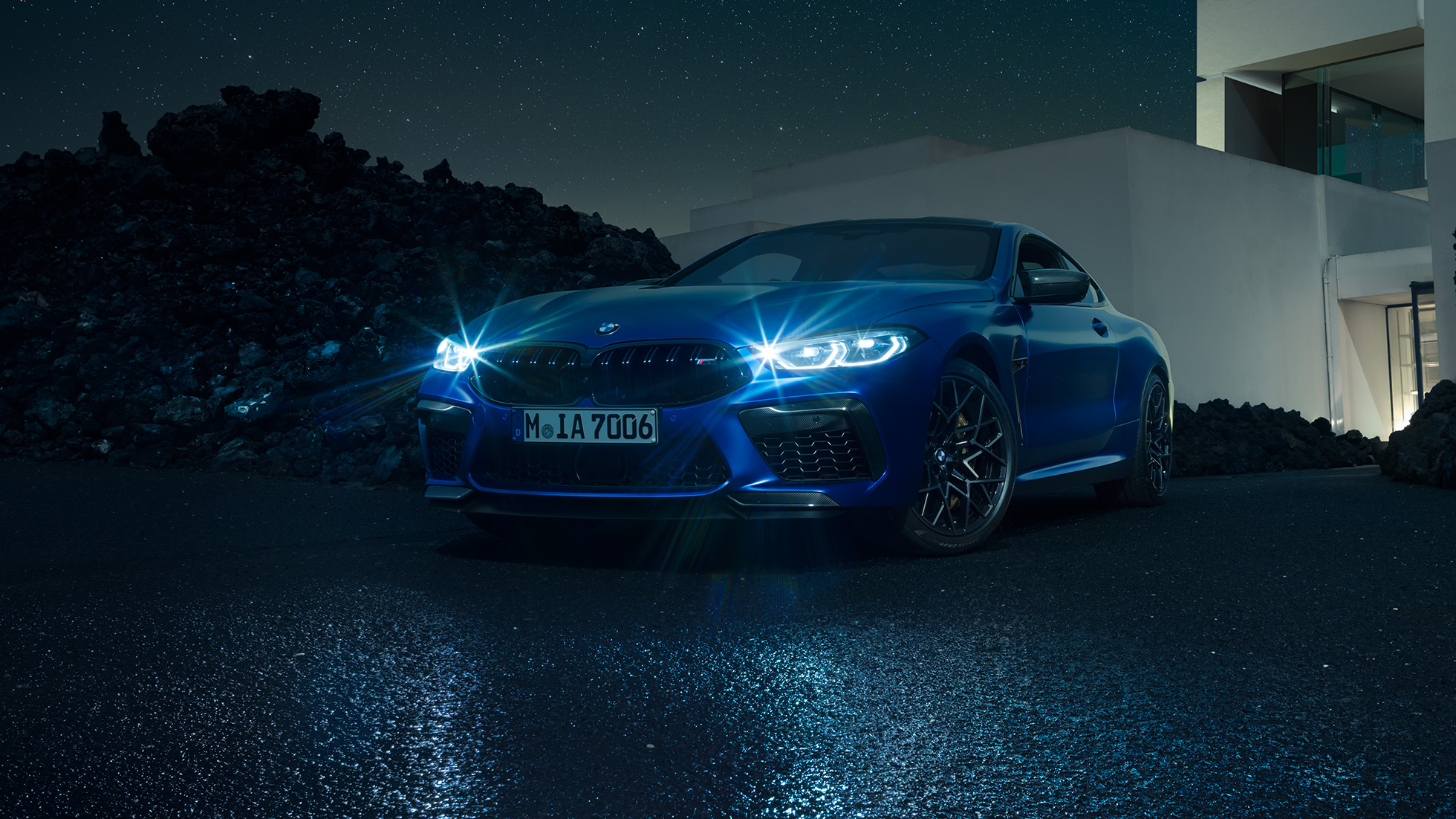 BMW M8 Competition Coupé, driekwart vooraanzicht F92. BMW M8 Competition Coupé in Marina Bay Blau metallic brandende LED Headlights, stilstaand driekwart vooraanzicht voor villa ‘s nachts F92.