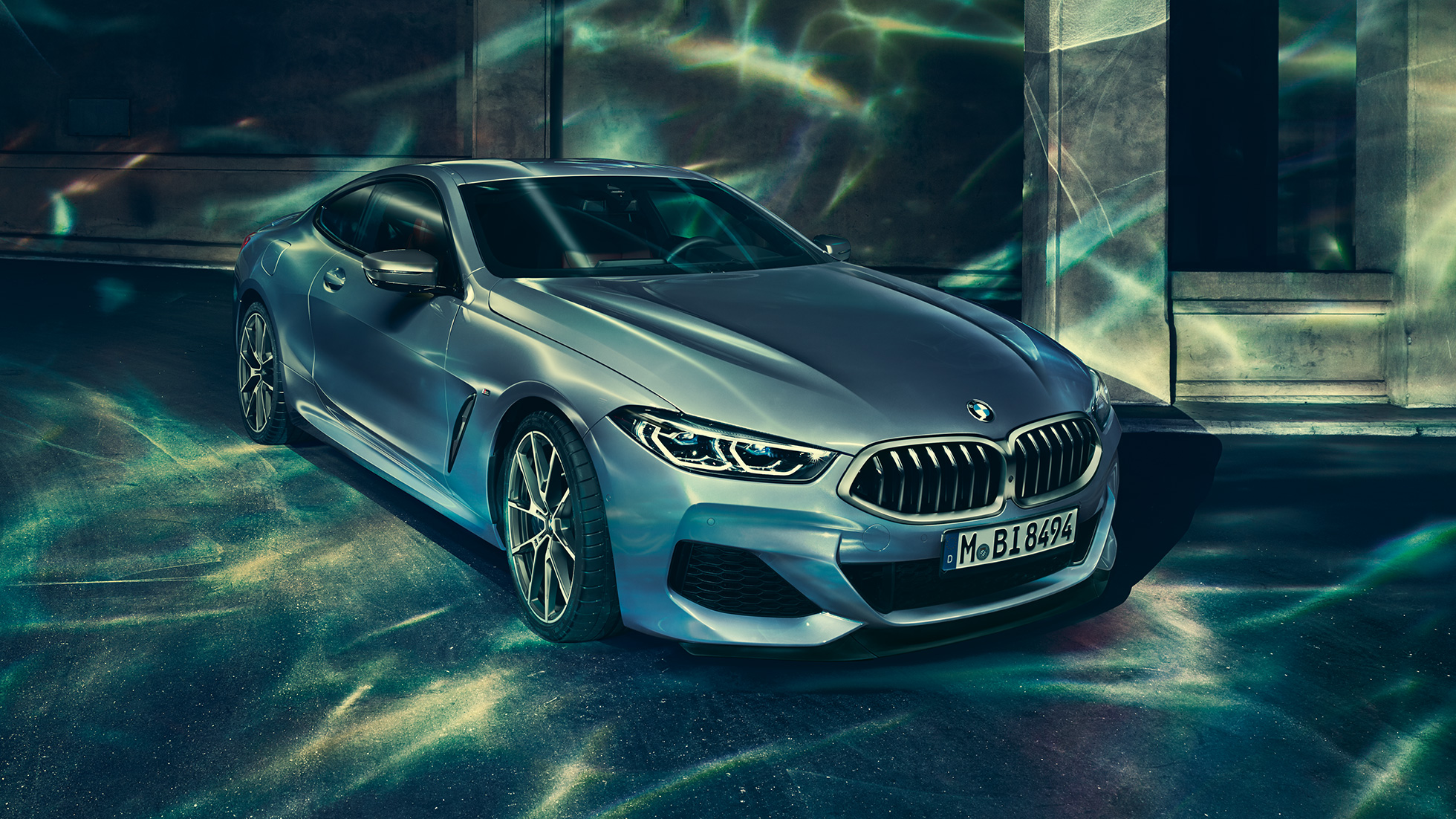 BMW M850i xDrive Coupé, driekwart vooraanzicht links G15. BMW M850i xDrive Coupé in Barcelona Blau metallic, driekwart vooraanzicht links, stilstaand voor gebouw G15.