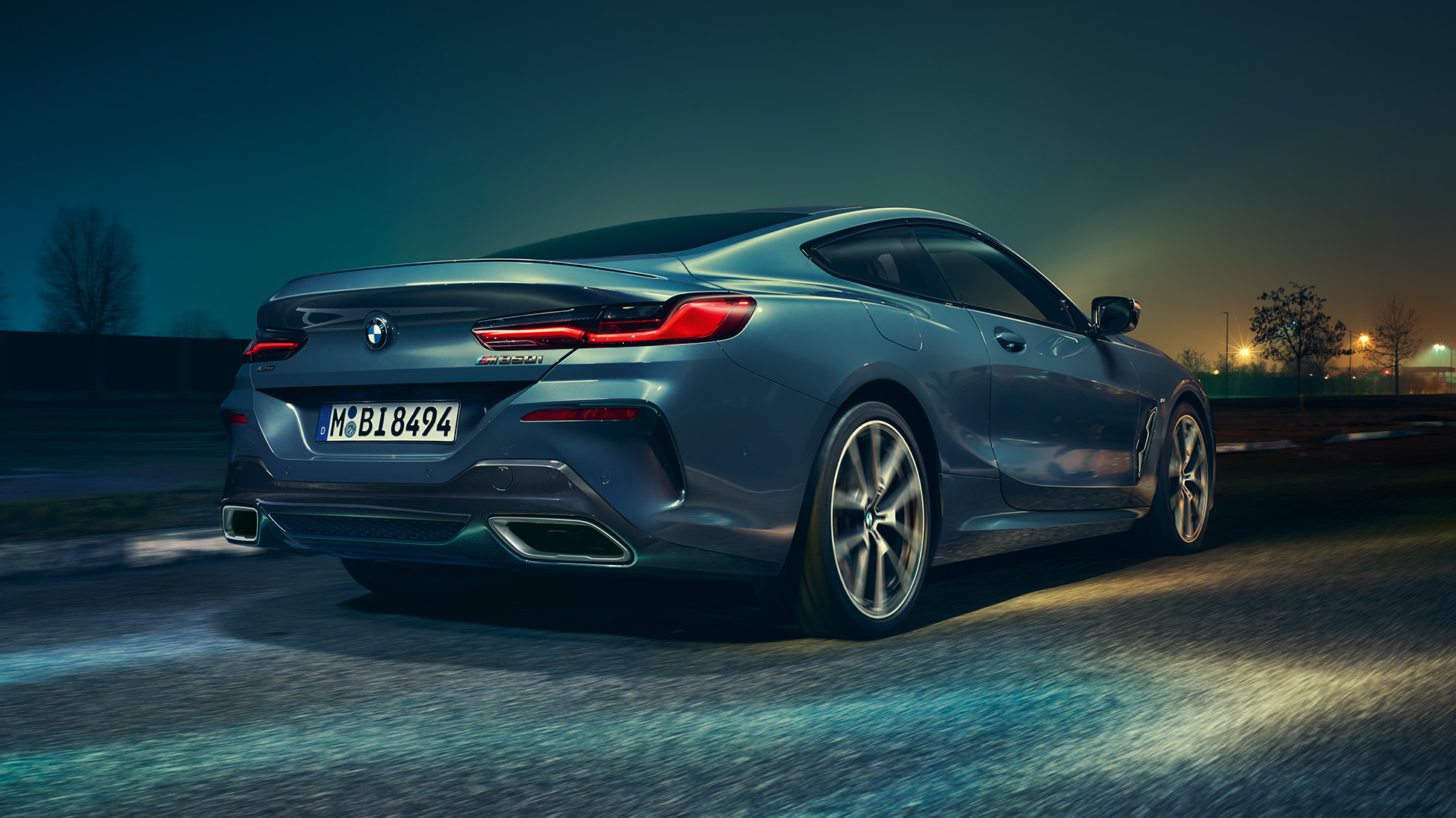BMW M850i xDrive Coupé, achteraanzicht G15. BMW M850i xDrive Coupé in Barcelona Blau metallic, achteraanzicht, in beweging ‘s nachts G15.
