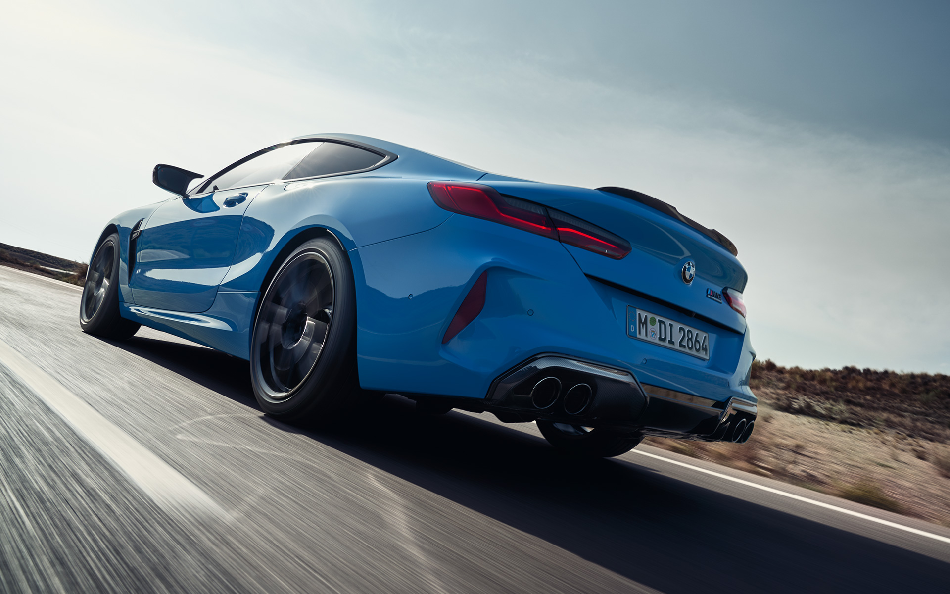 BMW M8 Competition Coupé F92 LCI 2022 driekwart achteraanzicht rijdend BMW M8 Competition Coupé F92 LCI facelift 2022 Daytona Beach Blau uni driekwart achteraanzicht rijdend op landweg