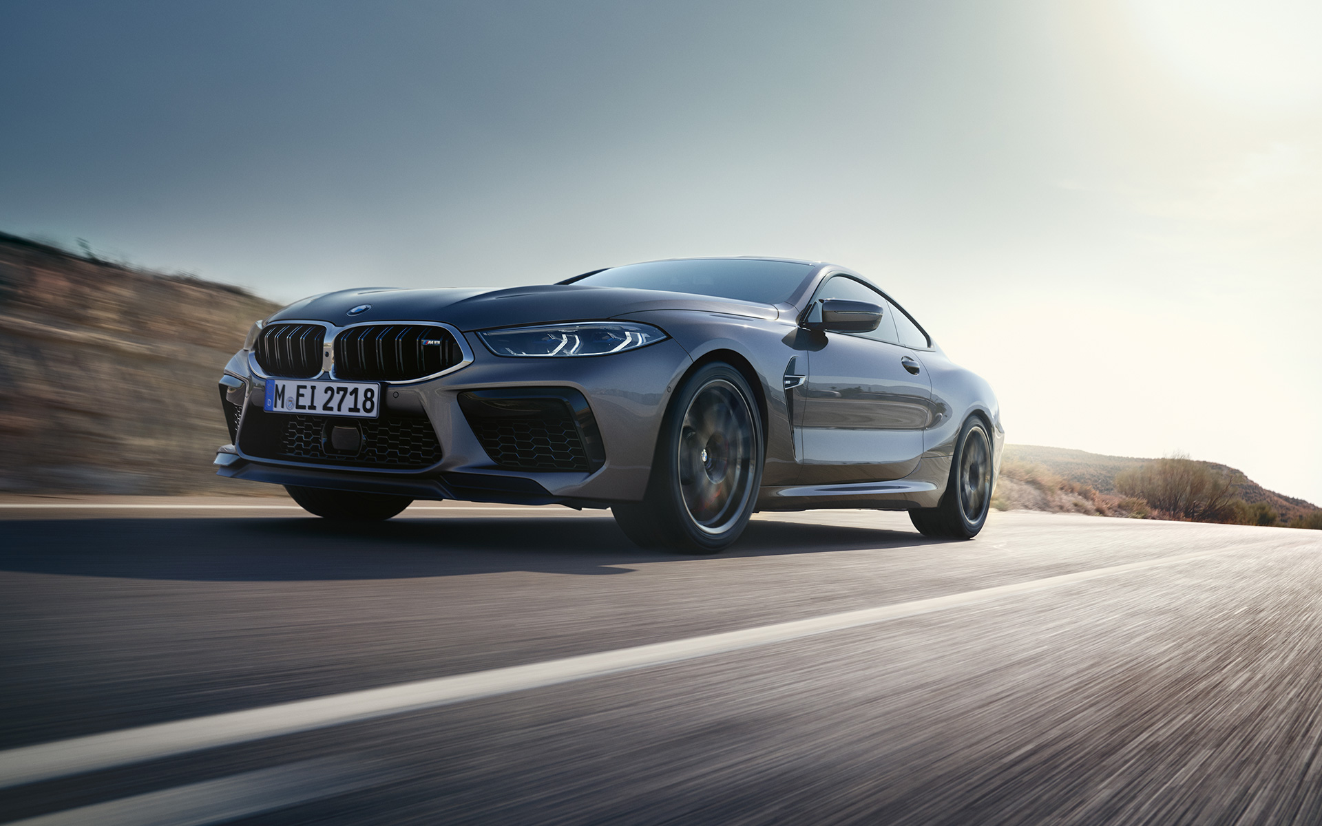 Driekwart vooraanzicht BMW M8 Coupé F92 LCI facelift 2022 rijdend op landweg BMW M8 Coupé F92 LCI facelift 2022 Skyscraper Grau metallic driekwart vooraanzicht rijdend op landweg kikvorsperspectief
