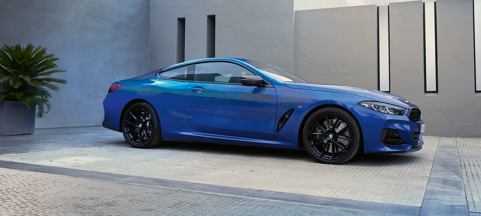 Zijaanzicht BMW M850i xDrive Coupé G15 LCI facelift 2022 BMW M850i xDrive Coupé G15 LCI facelift 2022 M Portimao Blau metallic zijaanzicht stilstaand voor gebouw