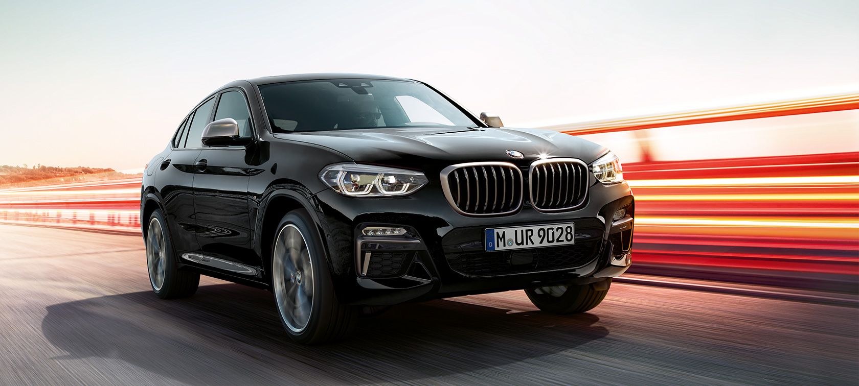 BMW X4 M40i et BMW X4 M40d, vue de trois quarts avant gauche G02. Extérieur des BMW X4 M40i et BMW X4 M40d en Saphierschwarz metallic, en mouvement, vue de trois quarts avant gauche avec bandes lumineuses G02.