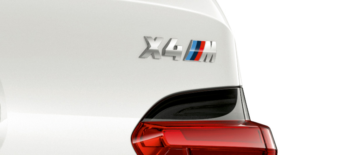 BMW X4 M, insigne du modèle F98. Extérieur de la BMW X4 M en Alpinweiß, vue en gros plan de l’arrière avec insigne du modèle F98.