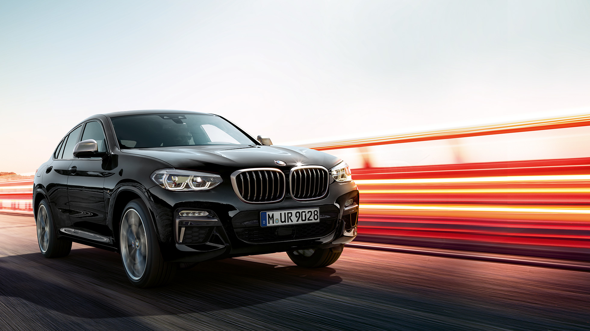 BMW X4 M40i, driekwart achteraanzicht G02. BMW X4 M40i in Saphirschwarz metallic, rijdend, exterieur, driekwart achteraanzicht met lichtstrepen G02.