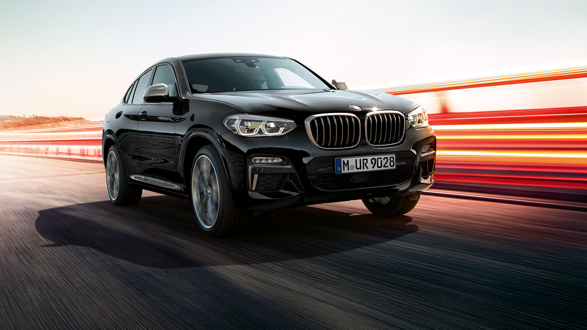 BMW X4 M40i en BMW X4 M40d, driekwart vooraanzicht G02. BMW X4 M40i en BMW X4 M40d in Saphirschwarz metallic, exterieur, driekwart vooraanzicht links met lichtstrepen G02.
