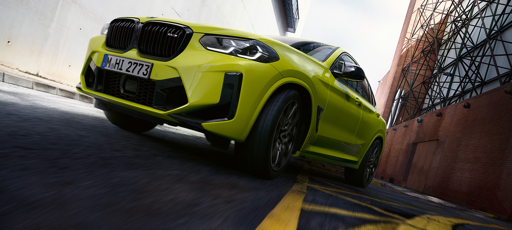 Driekwart vooraanzicht met onderaanzicht BMW X4 M Competition F98 LCI 2021 BMW X4 M Competition F98 LCI facelift 2021 Sao Paulo Gelb driekwart vooraanzicht met onderaanzicht rijdend door een smalle straat