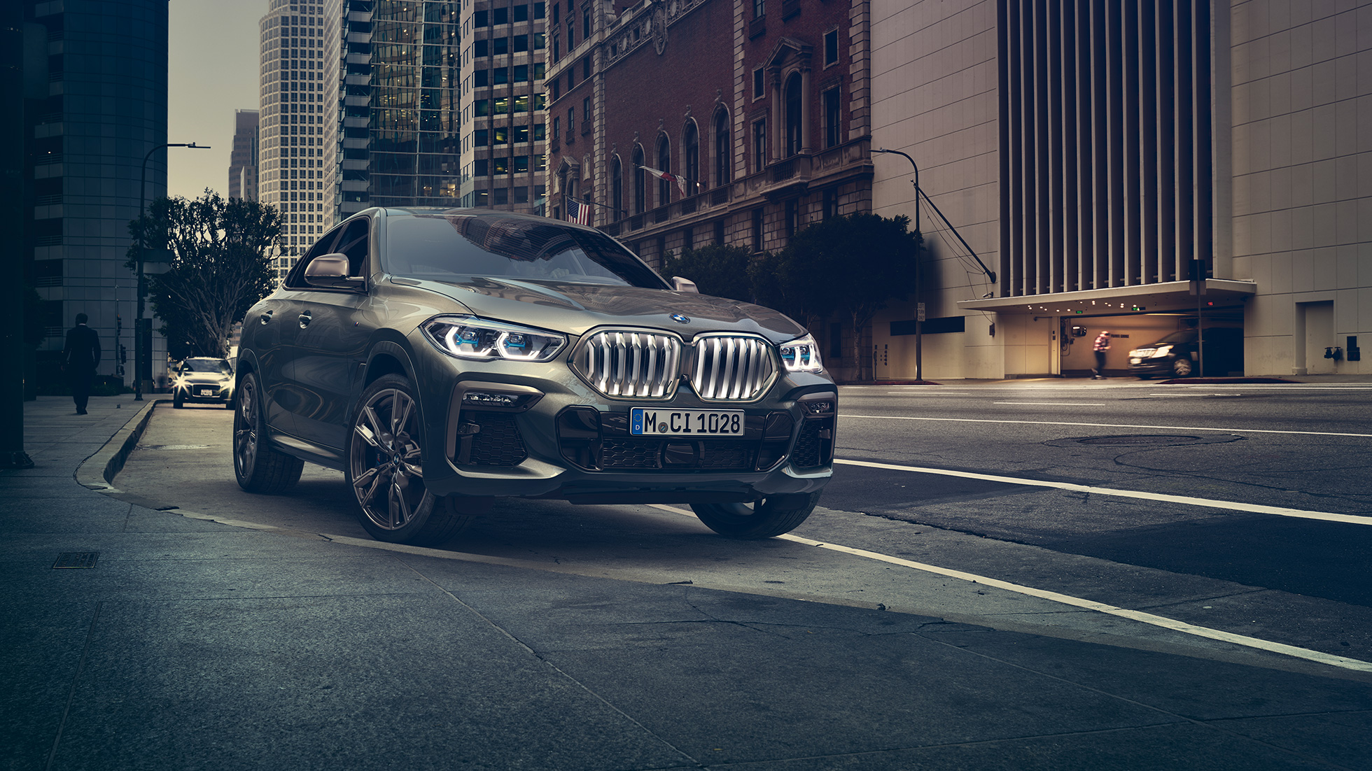BMW X6 M50i SUV à l’arrêt G06 La BMW X6 M50i SUV vue de trois quarts avant, à l’arrêt devant un décor urbain G06