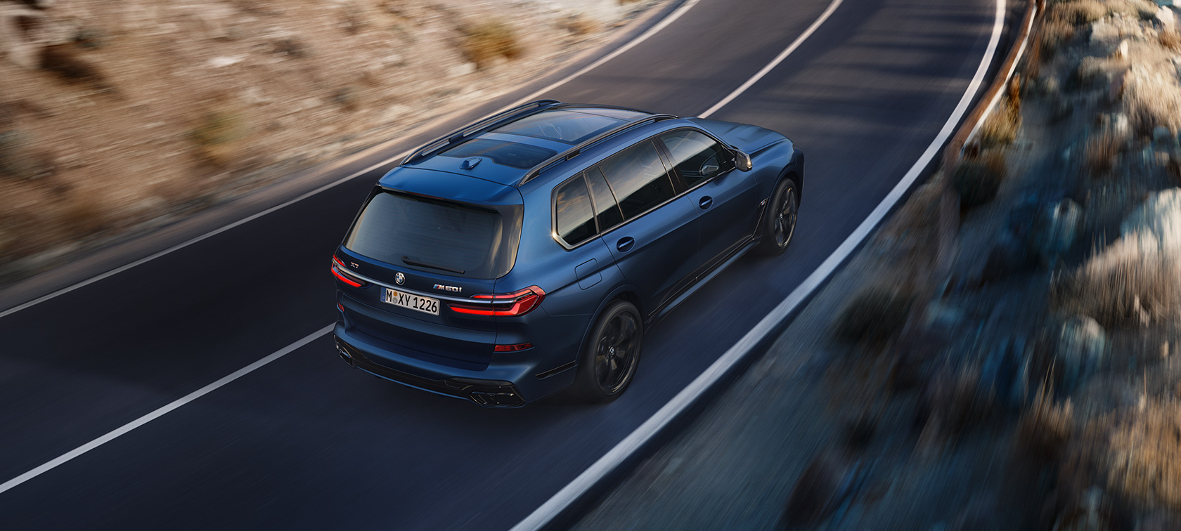BMW X7 M60i xDrive G07 LCI Frozen Marina Bay Blue Vue de trois quarts arrière perspective aérienne en mouvement BMW X7 M60i xDrive G07 LCI Frozen Marina Bay Blue Vue de trois quarts arrière perspective aérienne en mouvement sur la route