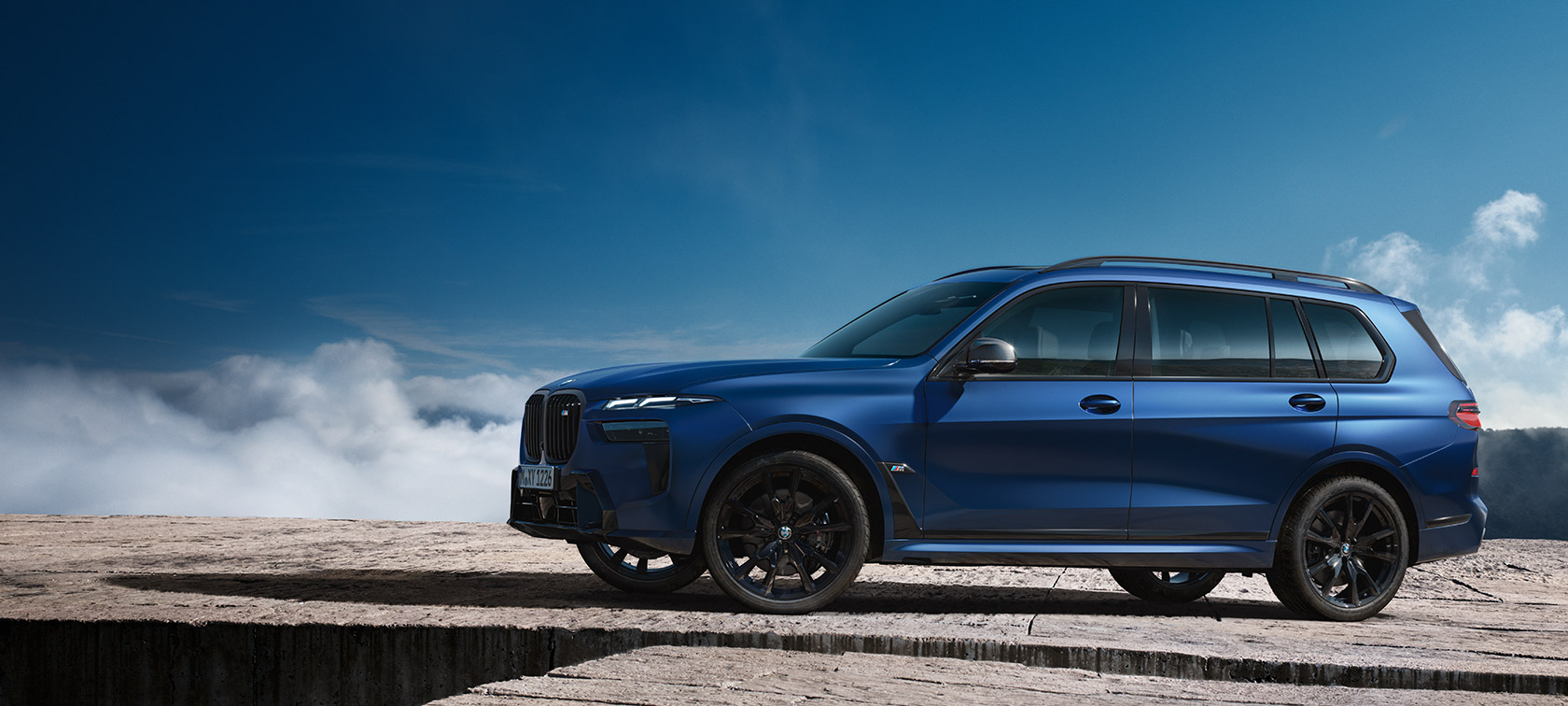 BMW X7 M60i xDrive G07 LCI Frozen Marina Bay Blue zijaanzicht stilstaand in berglandschap