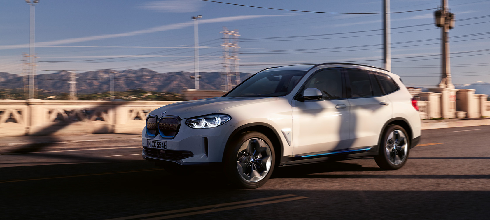 BMW iX3 SUV G08, vue de trois quarts avant en mouvement sur la route BMW iX3 SUV G08 2020 en Mineralweiß metallic, vue de trois quarts avant en mouvement sur la route