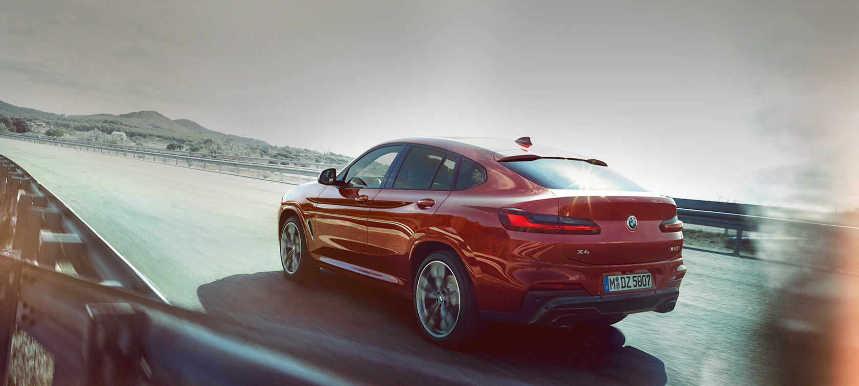 BMW X4 en mouvement sur la route G02 BMW X4 M40i G02 2018 en Flamencorot Brillanteffekt Rot Vue de trois quarts arrière en mouvement sur la route