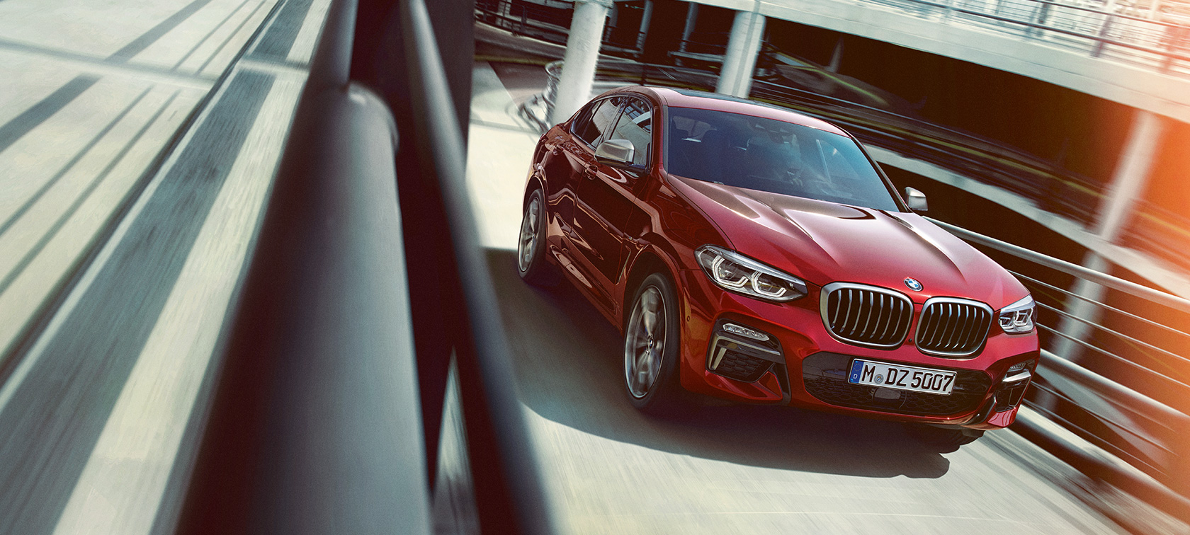 BMW X4 entrant dans un parking couvert G02 BMW X4 G02 2018 en Flamencorot Brillanteffekt, vue de trois quarts arrière, sortant d’un parking couvert