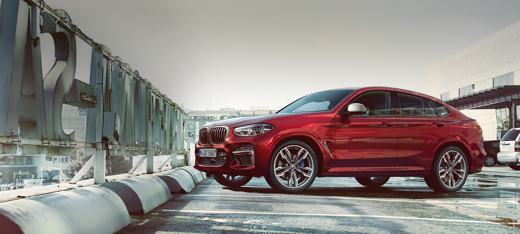 BMW X4 en stationnement, vue de profil G02 BMW X4 M40i G02 2018 en Flamencorot Brillanteffekt vue de profil en stationnement dans un parking à étages