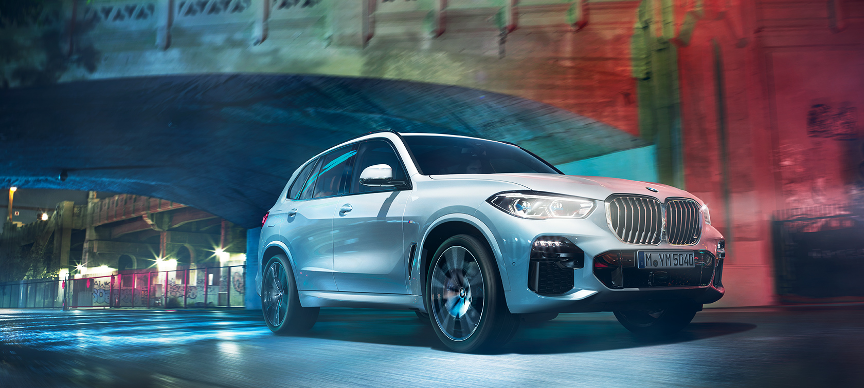 BMW X5 in actie De BMW X5 rijdt door de nachtelijke grootstad