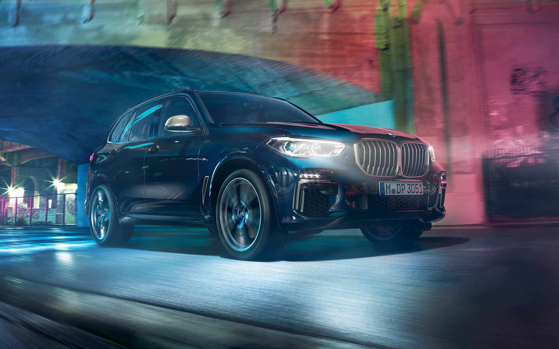 BMW X5 M50d in actie Opname van de rijdende BMW X5 ’s nachts met de stad als decor
