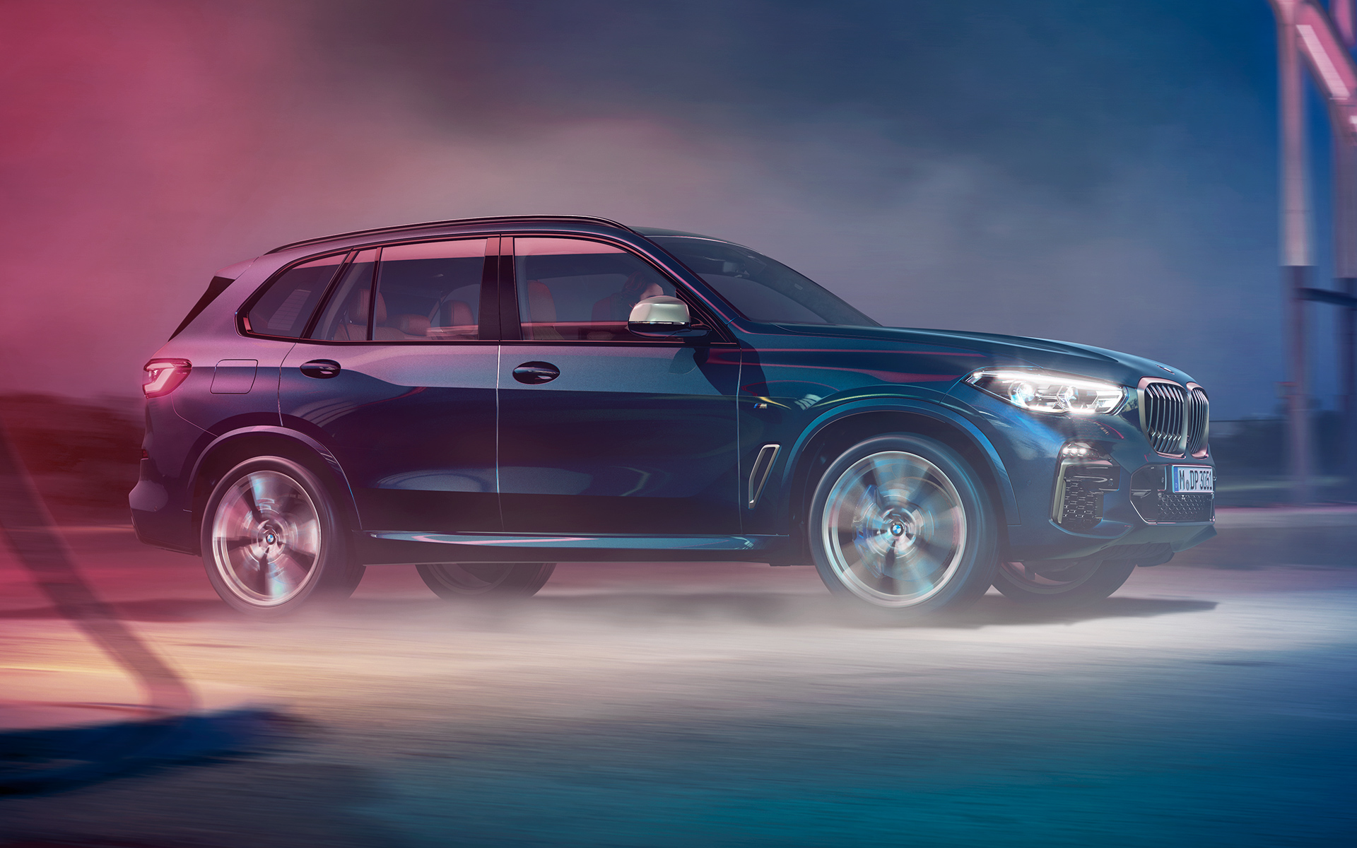 BMW X5 M50d rijdend Opname van de rijdende BMW X5 ’s nachts met de stad op de achtergrond