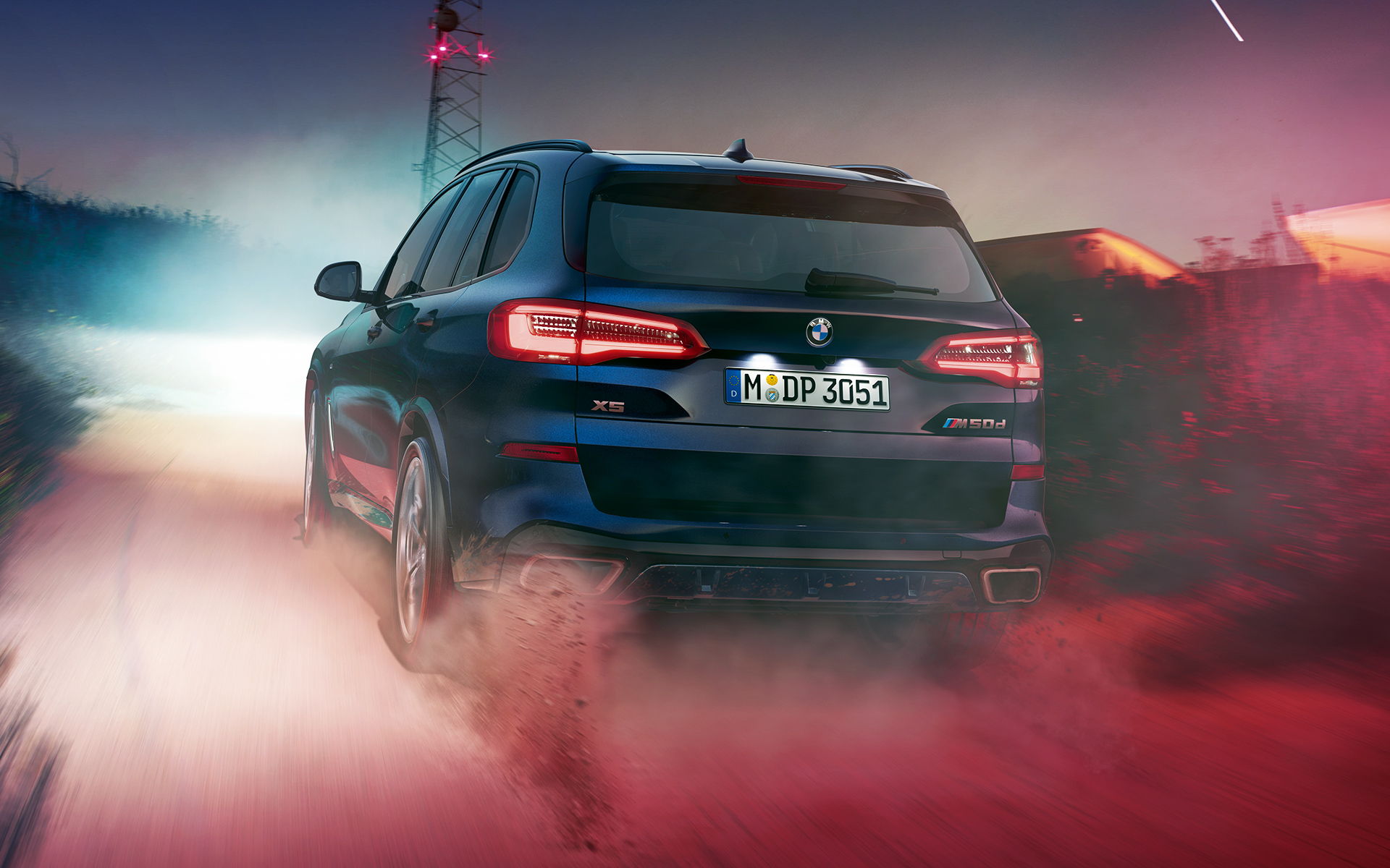 BMW X5 M50d achterzijde Achterkant van de BMW X5 ’s nachts met de stad als decor