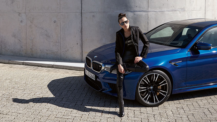Vrouw in BMW M kledij, zittend op een BMW M5. Vrouw in BMW M kledij, zittend op een BMW M5.