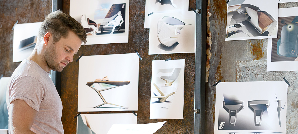 Schetsen van de BMW Vision iNEXT Man voor een muur vol met schetsen van de BMW Vision iNEXT
