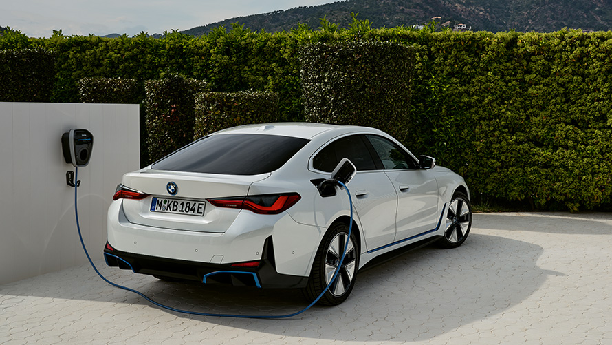 Laden aan de BMW Wallbox Gen 3 BMW i4 G26 BEV driekwart achteraanzicht BMW i4 G26 BEV driekwart achteraanzicht ladend aan de BMW Wallbox Gen 3 voor haag
