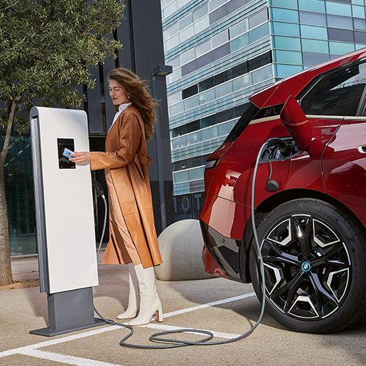 BMW iX i20 aan laadpaal BMW iX i20 aan laadpaal Vrouw met BMW Charging Card