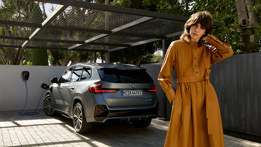 BMW X1 Plug-in Hybrid 2022 U11 vue arrière branchée à une borne avec modèle BMW X1 Plug-in Hybrid 2022 U11 vue arrière branchée à une borne avec modèle