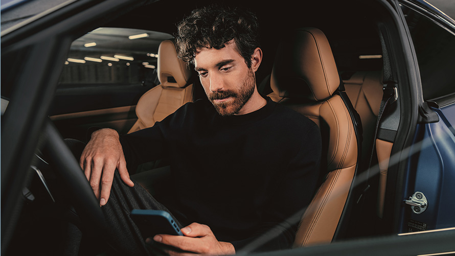 Man zit in BMW Man zit in BMW en kijkt op zijn smartphone
