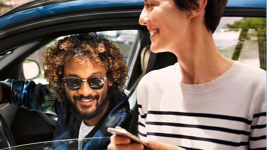 App My BMW Un homme et une femme hors de la BMW qui utilisent l’App My BMW sur smartphone