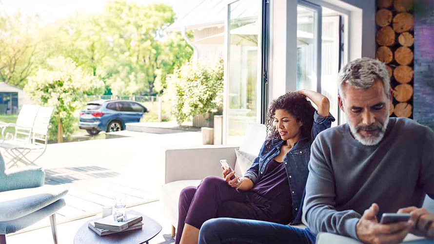 Remote Services Un homme et une femme assis dans un fauteuil utilisent les Remote Services sur un smartphone.