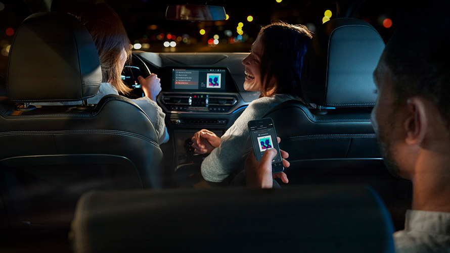 Connected Command Connected Command : trois personnes sont assises dans une BMW et écoutent de la musique durant le trajet.