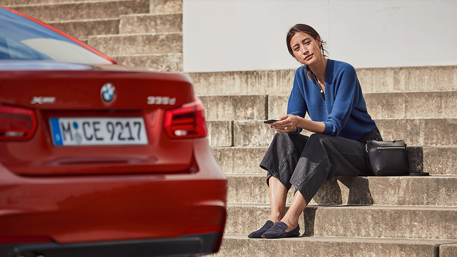 Service et dépannage Une femme est assise devant une BMW rouge et utilise l'assistance Service et dépannage.