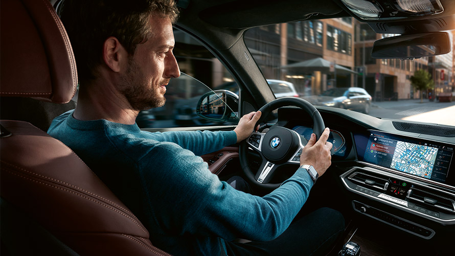 Assistant de recherche de place de stationnement Un homme utilise l'assistant de recherche de place de stationnement sur l'écran de la BMW.