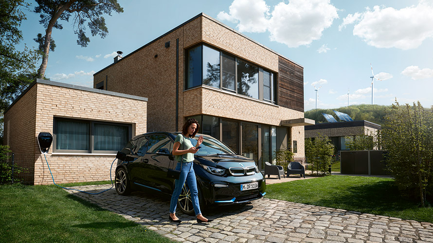 Digital Charging Service Une femme sort de sa BMW i3 et utilise le Digital Charging Service sur son smartphone.