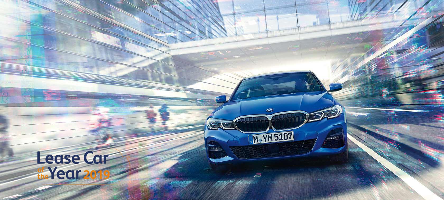 BMW Série 3 Berline, vue de face. G20 Vue de face de la BMW Série 3 Berline en mouvement de jour sous des immeubles de verre. G20