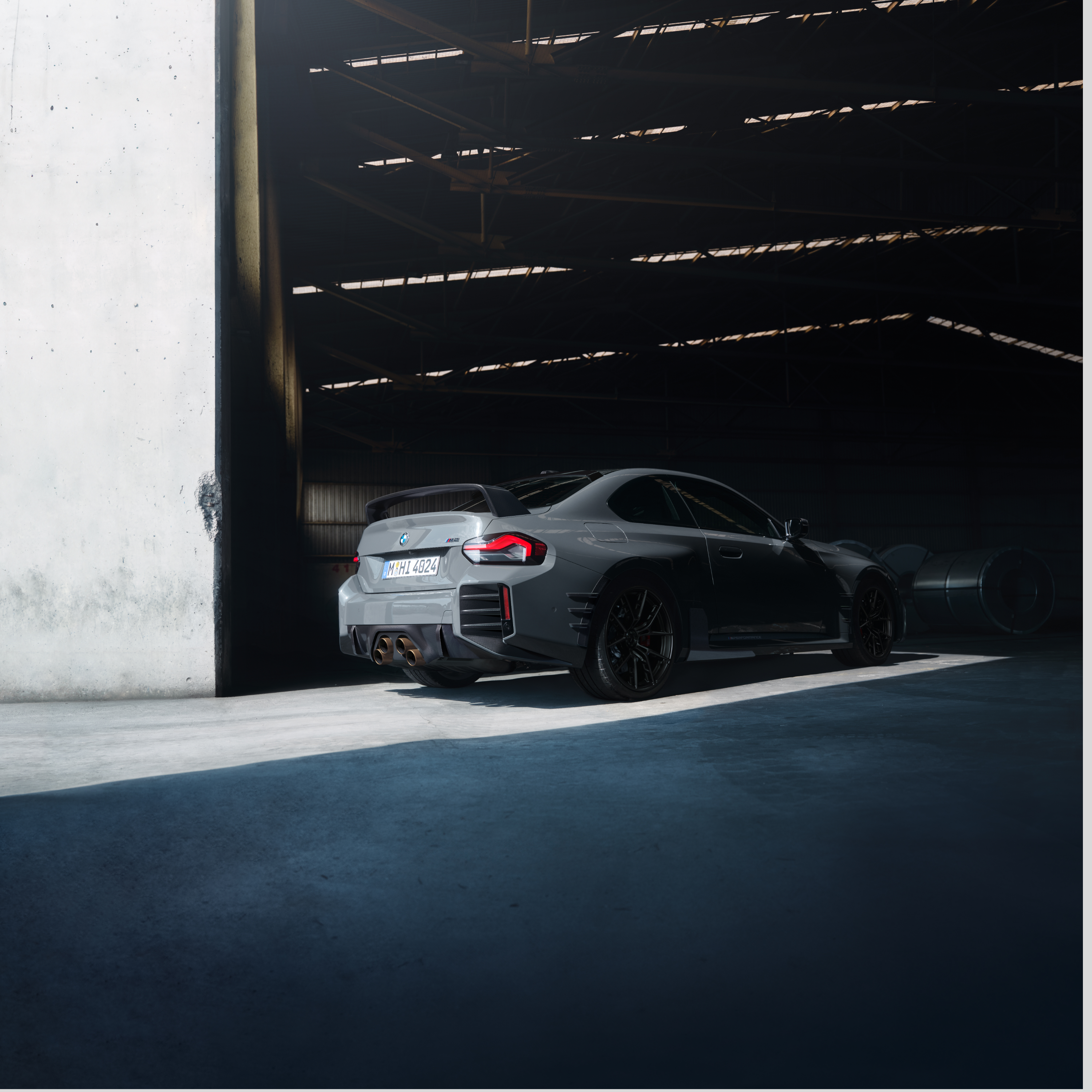 Une BMW est stationnée devant le portail d’un grand hall