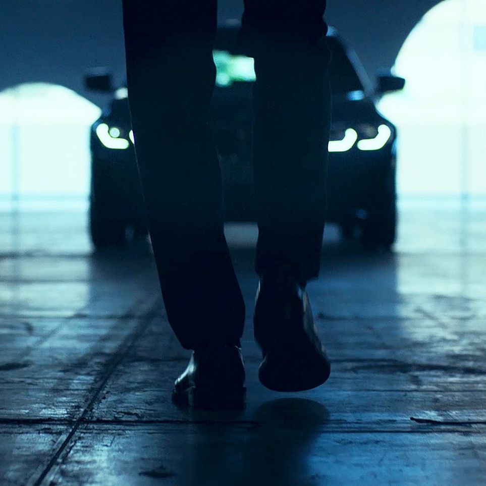Avant de la BMW Série 3 Berline. G20 Vue de l’arrière d’un homme marchant devant la BMW Série 3 Berline sur l’asphalte. G20