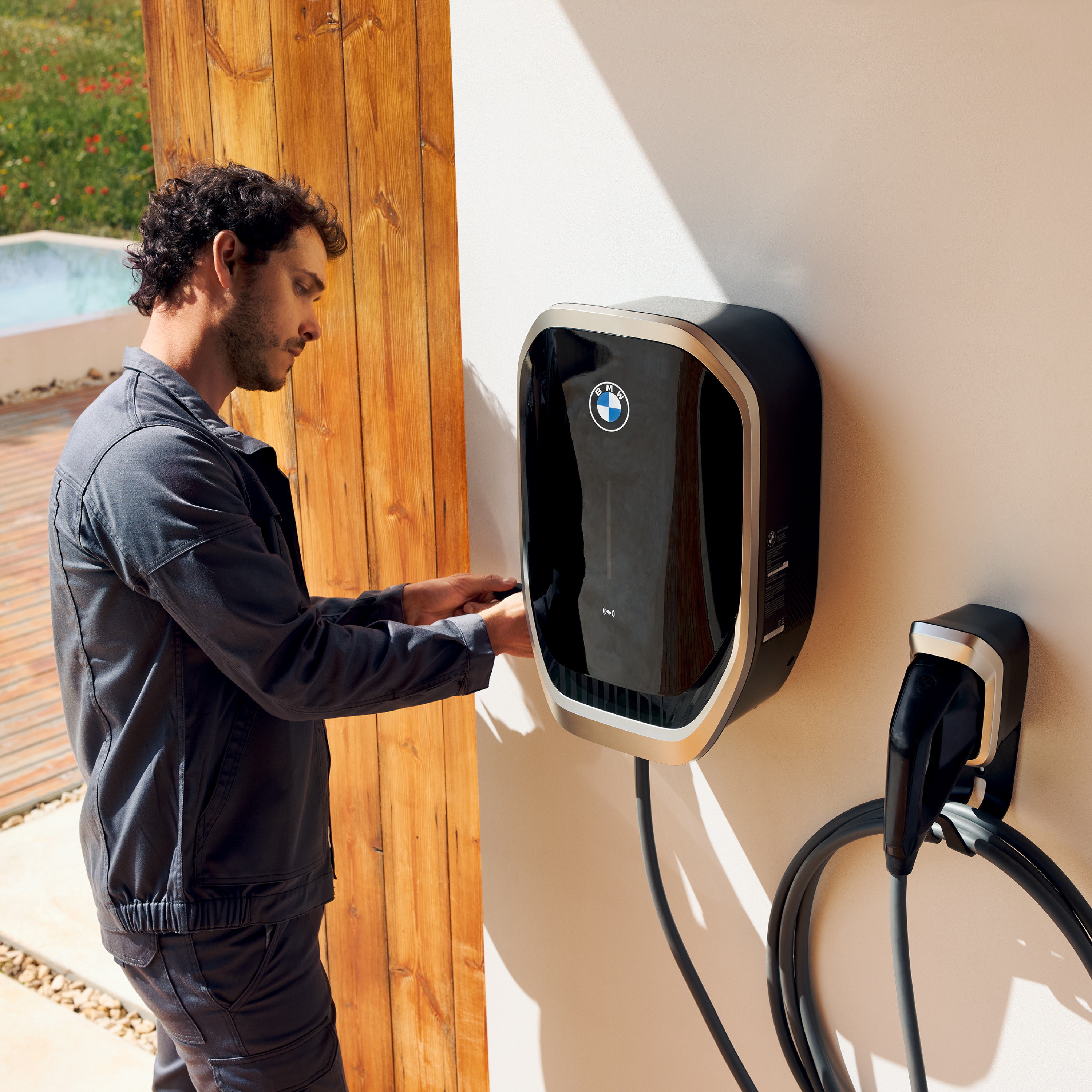 Eén persoon sluit een laadkabel aan op een BMW wallbox